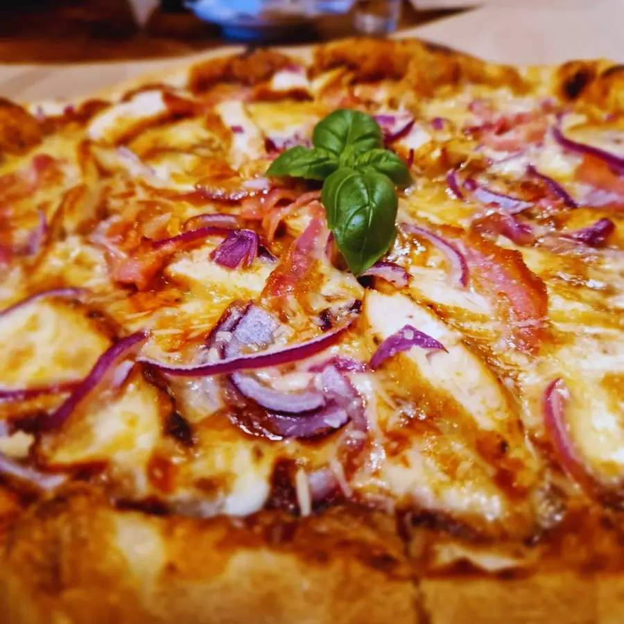 Pizza z czerwoną cebulą i listkiem bazylii pośrodku.