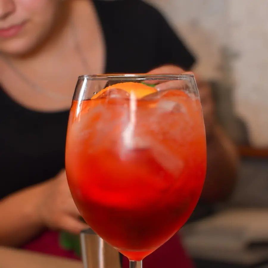 Kieliszek pomarańczowego drinka z lodem, trzymany przy stole.