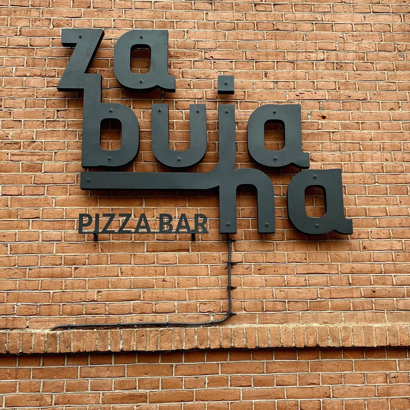 Znak Zabujanej – przestrzenne litery na ceglanej ścianie lokalu.
