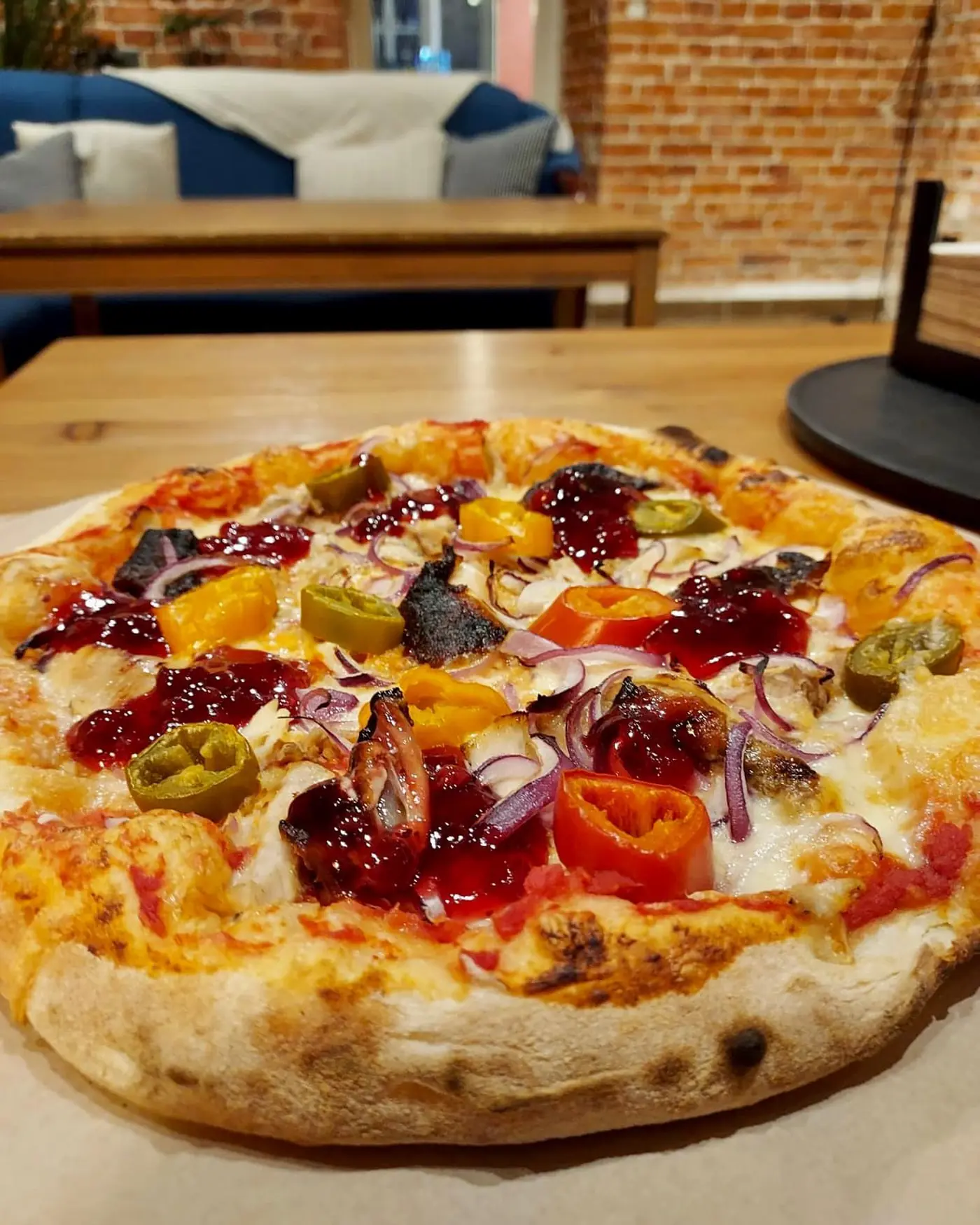 Pizza z gęsiną, żurawiną i papryką na drewnianym blacie.