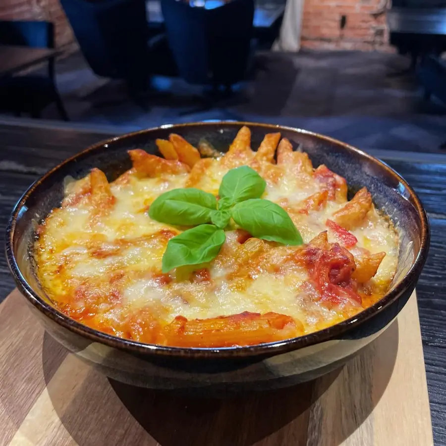 Zapiekany makaron w ciemnej misie, z serem i bazylią.
